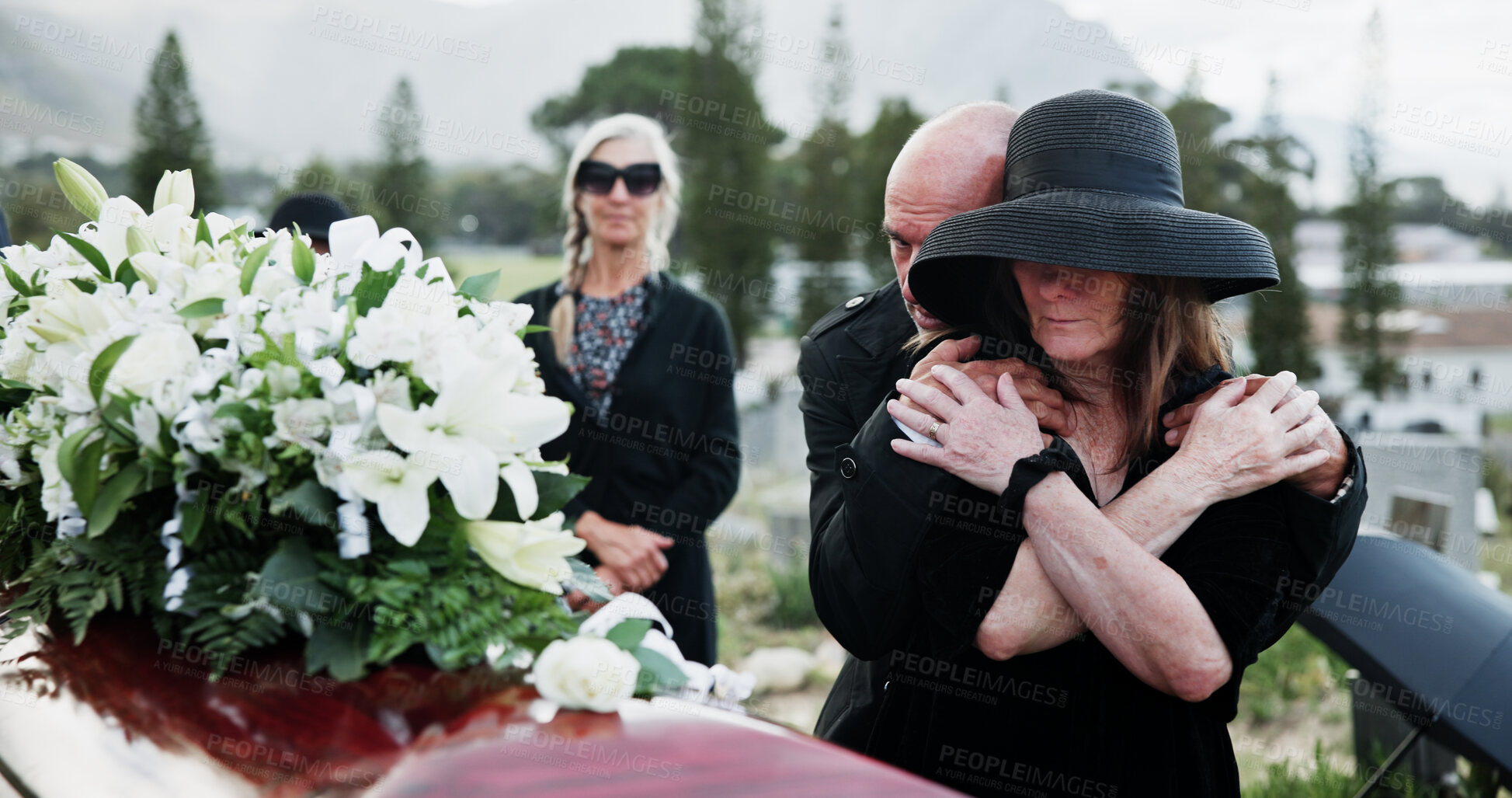 Buy stock photo Flowers, sad and people in cemetery, comfort for grief and compassion with burial for death ceremony. Family, memorial service and group in graveyard, mourning loss and crying with support or emotion