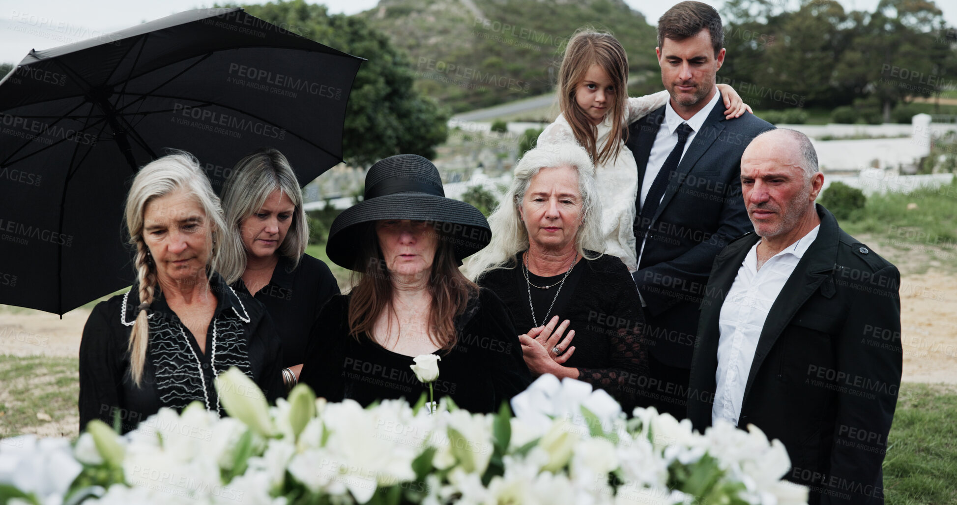 Buy stock photo Sad, people and funeral in graveyard with flowers, support or grief for burial ceremony of loved one. Family, death and mourning in cemetery outdoor with white rose, bereavement and memorial service.