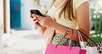 Phone, shopping bag and typing with hands in city for communication, online promotion and sale. Digital coupon, store credit check and contact with person outdoor for customer rewards app and retail