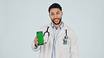 Green screen, man and portrait of doctor with phone in studio for clinic sign up, FAQ and telehealth. Cellphone, happy and healthcare worker on mobile app for medical information by white background.