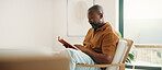 Reading, home and mature man with book for hobby, information and knowledge on break. House, weekend and African person with literature, novel and story for rest, relax and peace for afternoon