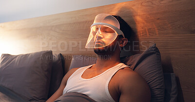 Buy stock photo Man, skincare and light with uv mask in bed for beauty, facial or anti aging treatment in home. Relax, male person or LED cosmetics for skin protection, collagen or blood circulation in bedroom