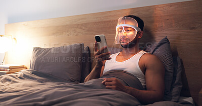 Buy stock photo Phone, relax and man with mask for skincare, research and browsing web for light therapy benefits. Bed, person and led cosmetic in home with facial tech, beauty tips and mobile app for acne treatment