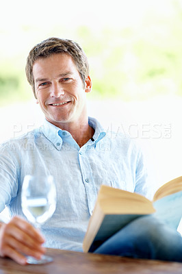 Buy stock photo Smile, man and wine glass on patio with book, peace and calm morning at holiday resort. Portrait, male person and terrace with novel, champagne and weekend break at luxury accommodation on vacation