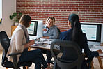 Business woman talking to colleagues in office discussing finance information on computer screens