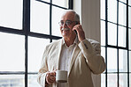 Senior businessman using smartphone talking on mobile phone having phone call drinking coffee by window