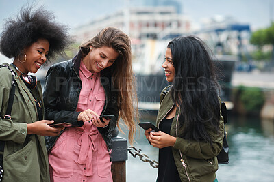 Buy stock photo Hangout, phone and smile of women on promenade together for bonding, connection or typing. App, social media and text message with girl friends outdoor by ocean for browsing, response or reunion