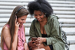 Best friends listening to music using smartphone sharing headphones in city