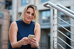 Business woman using smartphone sitting on stairs in city