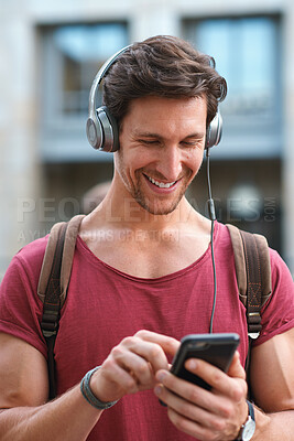 Buy stock photo Phone, headphones and man in city with texting, chatting or contact on mobile app with music. Cellphone, audio tech and male person with connectivity on website with listening to playlist in town.