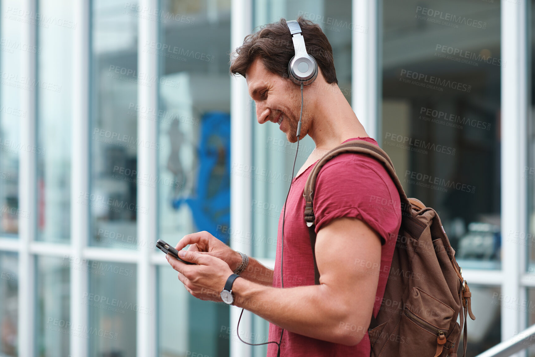 Buy stock photo Cellphone, headphones and man in city with texting, chatting or contact on mobile app with music. Phone, audio tech and male person with connectivity on website with listening to playlist in town.