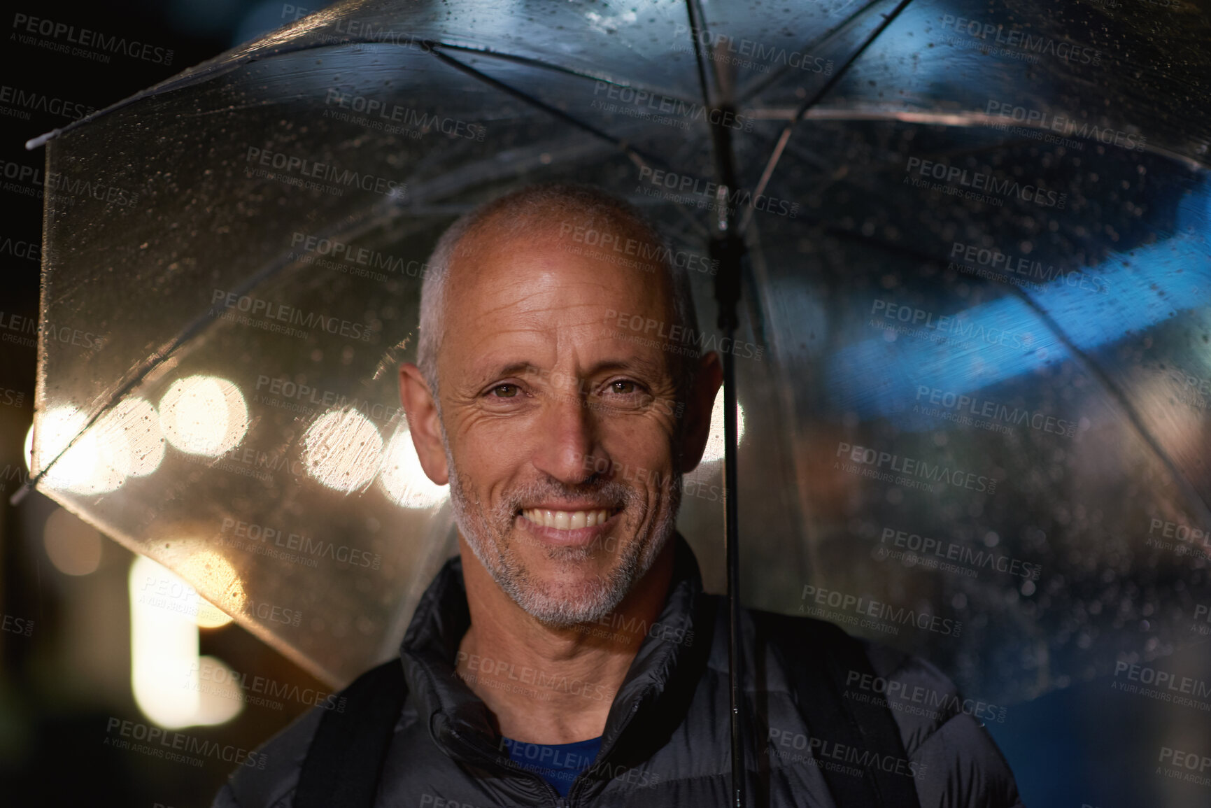 Buy stock photo Portrait, man and rain with umbrella for night, cold weather and evening commute outdoor from work. Late, bokeh and mature person smile by city lights with winter, water droplets and travel from job.