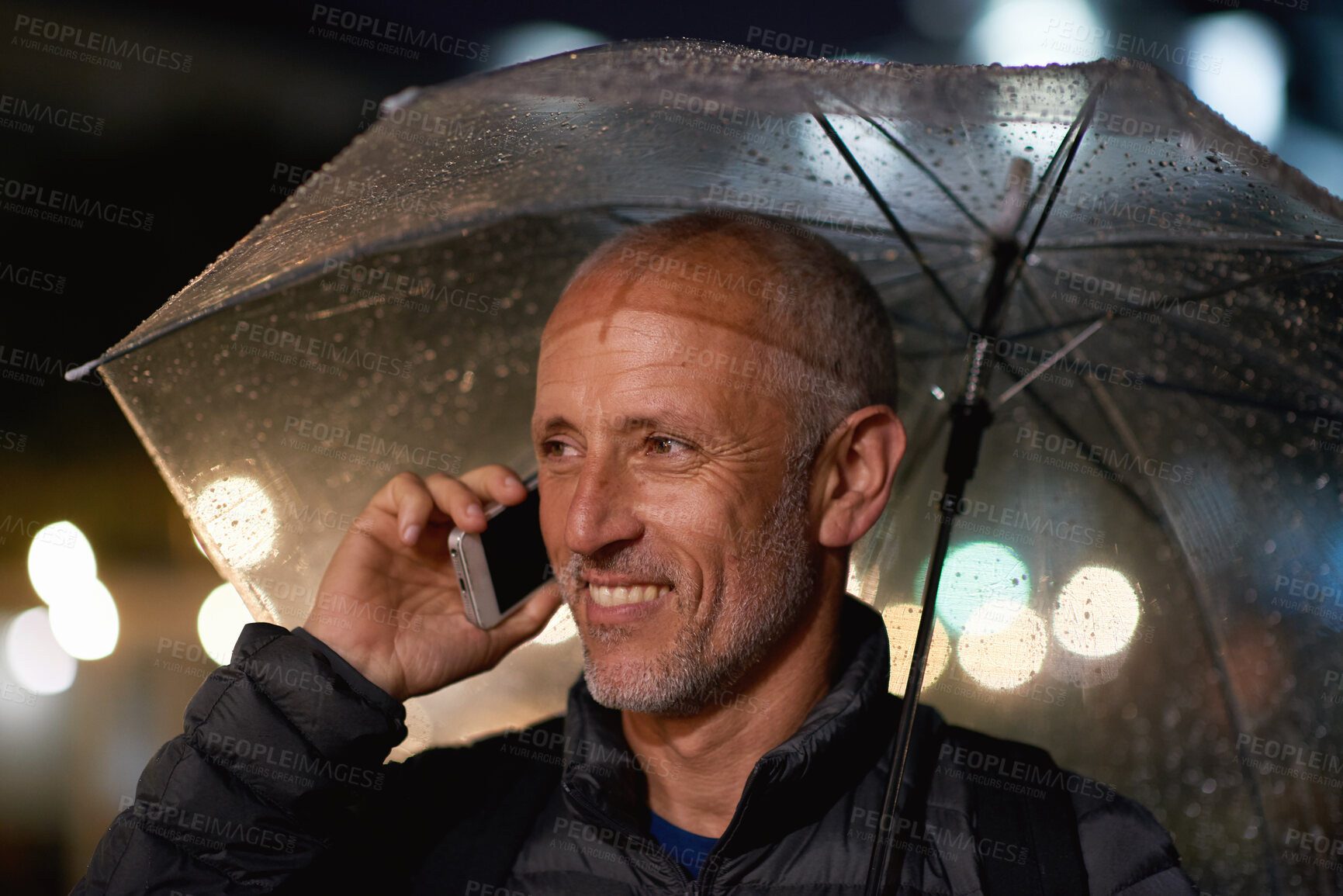 Buy stock photo Outdoor, umbrella and man with phone call at night, digital communication and commute for networking. Smile, rain and mature person with mobile for online conversation, bokeh and late travel in city