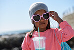 Portrait of little girl drinking milkshake on beach wearing sunglasses having fun summer vacation