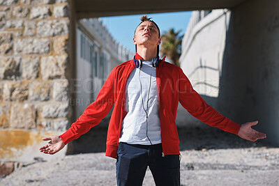 Buy stock photo Freedom, eyes closed and teenage boy outdoor for development, hope or inspiration. Arms out, headphones and wellness with adolescent male on concrete in nature for growth, independence or liberty