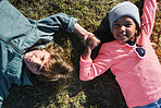 Portrait little boy and girl holding hands lying on grass in park