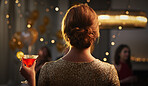 Elegant woman dressed in gold holding cocktail