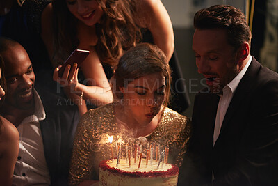 Buy stock photo Night, friends and woman with birthday cake at party, celebration and social event for reunion. Blow candles, photography and happy people with dessert for special day, milestone or late get together