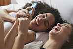 Beautiful Girl Friends using smart phone technology at home having fun laughing on weekend