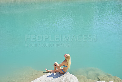 Buy stock photo Relax, sunbathing and woman on cliff for holiday, adventure and summer getaway in bikini. Above, female person and suntanning on coastal rock with space, scenic view and quarry water on vacation trip