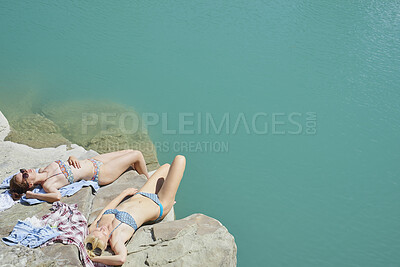 Buy stock photo Relax, sea and girl friends on rock in summer on holiday, getaway or weekend trip with travel. Sunbathing, space and female people in bikini on cliff for break of swimming by ocean water on vacation.