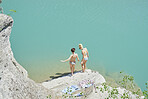 Beautiful girl friends testing water to wild swim in beautiful blue freshwater river on summer adventure vacation in nature