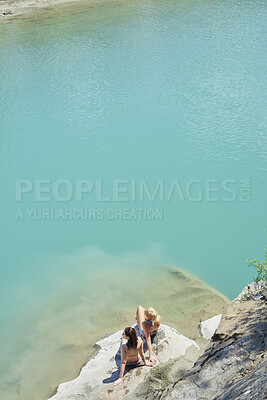 Buy stock photo Sunbathing, ocean and girl friends on rock in summer on holiday, getaway or weekend trip with travel. Relax, space and female people in bikini for swimming break by sea water on vacation from above.