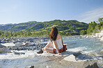 Travel adventure woman sitting on rock in river enjoying scenery view on vacation