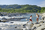 Brave girl friends cross river on travel adventure helping each other explore beautiful nature 