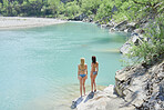 Adventure girl friends enjoying view of beautiful blue freshwater river stream wild landscape