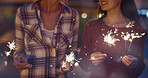 Beautiful Girl friends celebrating with sparklers having fun laughing for holiday friendship