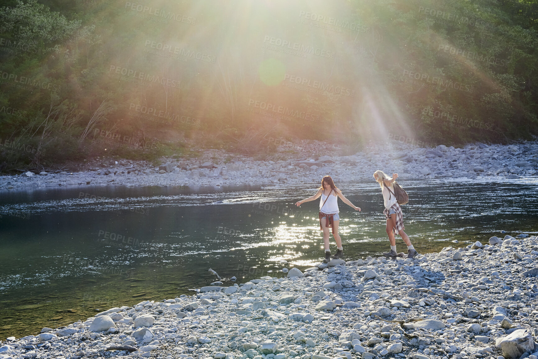 Buy stock photo Travel, walk or friends at lake with stones, fun time and bonding trip on summer break. Sunshine, space or women outdoor with adventure, vacation connection or hangout activity with balance on rock.