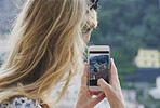 Beautiful girl takes photographs of Italy coast using smart phone technology for social media while on adventure travel vacation