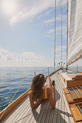 Buy stock photo Woman, relax and phone on yacht for travel, adventure and sailing with social media update on holiday. Female person, ocean getaway and mobile app on boat, deck and back view with horizon and texting
