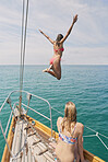 Beautiful girl jumping into blue sea from luxury wooden sailboat fun happy lifestyle ocean vacation travel