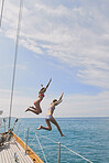Beautiful woman friends jumping into blue sea from luxury wooden sailboat fun happy lifestyle ocean vacation travel