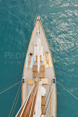 Buy stock photo Women, relax and travel in ocean with boat, summer holiday and sunbathing on deck for luxury getaway. Above, friends rest and journey at sea with yacht, tourist adventure and paradise for vacation.