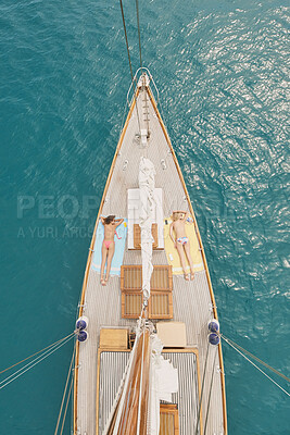 Buy stock photo Women, travel and sunbathing in ocean with boat, summer holiday and relax together for luxury getaway. Above, friends rest and journey at sea with yacht, tourist adventure and tanning for vacation.
