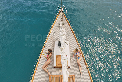 Buy stock photo Peace, travel and relax with friends on yacht for summer vacation, suntanning and seaside adventure. Calm, sailing and tropical cruise with above of women on boat for ocean expedition and journey
