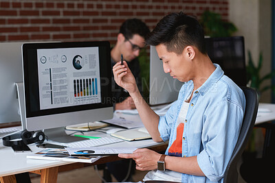Buy stock photo Computer screen, documents and reading with designer man at desk for review of statistics. Data, digital and paperwork with design employee in workplace for analysis of charts, graphs or metrics