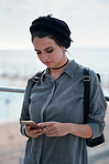 Beautiful woman using smartphone on seaside browsing social media messages texting with mobile phone