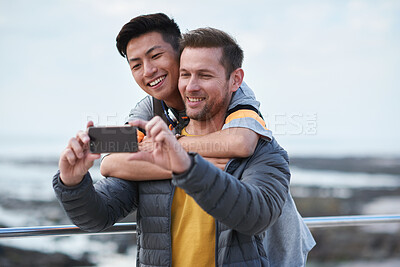Buy stock photo Hug, love and selfie with gay couple at beach together for bonding, memories or travel. App, photograph and vacation with lgbt men embracing for holiday, interracial relationship or security
