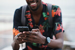 African american travel man using smartphone on beach texting with mobile phone sharing summer vacation wearing colorful hawaiian shirt