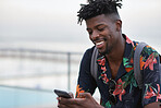 African american travel man using smartphone on beach texting with mobile phone sharing summer vacation wearing colorful hawaiian shirt