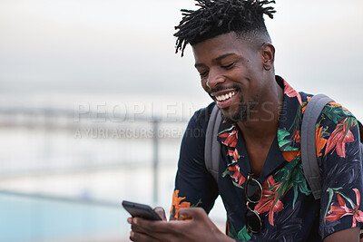Buy stock photo Happy, travel and black man with phone on beach promenade for online chatting or texting in nature. Male person, traveler or tourist with smile on smartphone for mobile network, app or connection