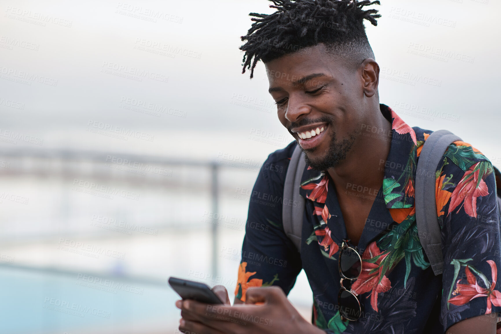 Buy stock photo Happy, travel and black man with phone on beach promenade for online chatting or texting in nature. Male person, traveler or tourist with smile on smartphone for mobile network, app or connection