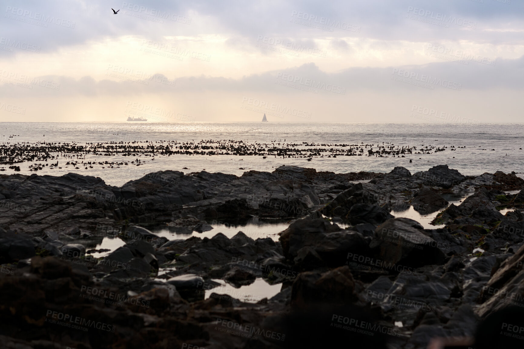 Buy stock photo Horizon, overcast and yacht with view of ocean from seaside for holiday, travel or vacation. Clouds, rocky and seascape with boat on water for adventure cruise, voyage or weekend getaway in morning