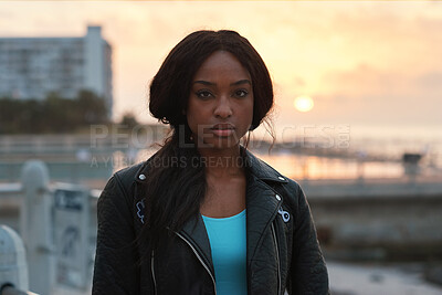 Buy stock photo Black woman, portrait and travel by beach with sunset, serious expression or trip abroad. Female traveler, nature or twilight with summer sky, vacation and person outdoor for exploring on holiday