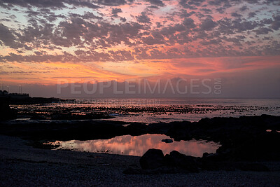 Buy stock photo Rocks, space and sunset with view of ocean from seaside for background or scenic wallpaper. Clouds, seascape and sky with water in colorful environment for calm dusk, nightfall or twilight scenery