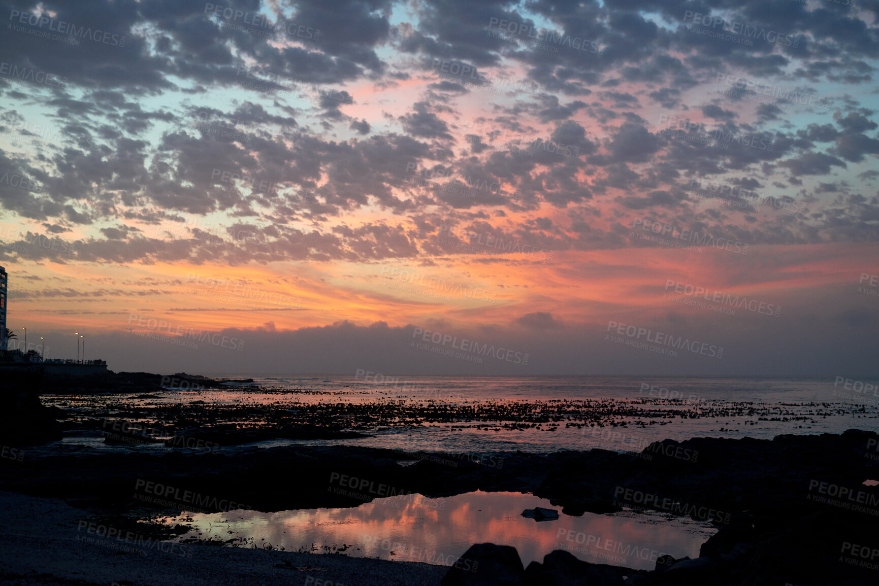 Buy stock photo Rocky, sky and sunset with view of ocean from seaside for background or scenic wallpaper. Cloudy, seascape and space with water in colorful environment for calm dusk, nightfall or twilight scenery